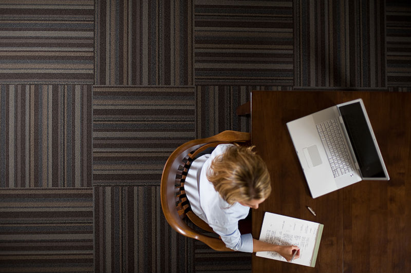 A woman seated on commercial flooring tile works at a computer. Chattanooga commercial photography by Dotson Studios.